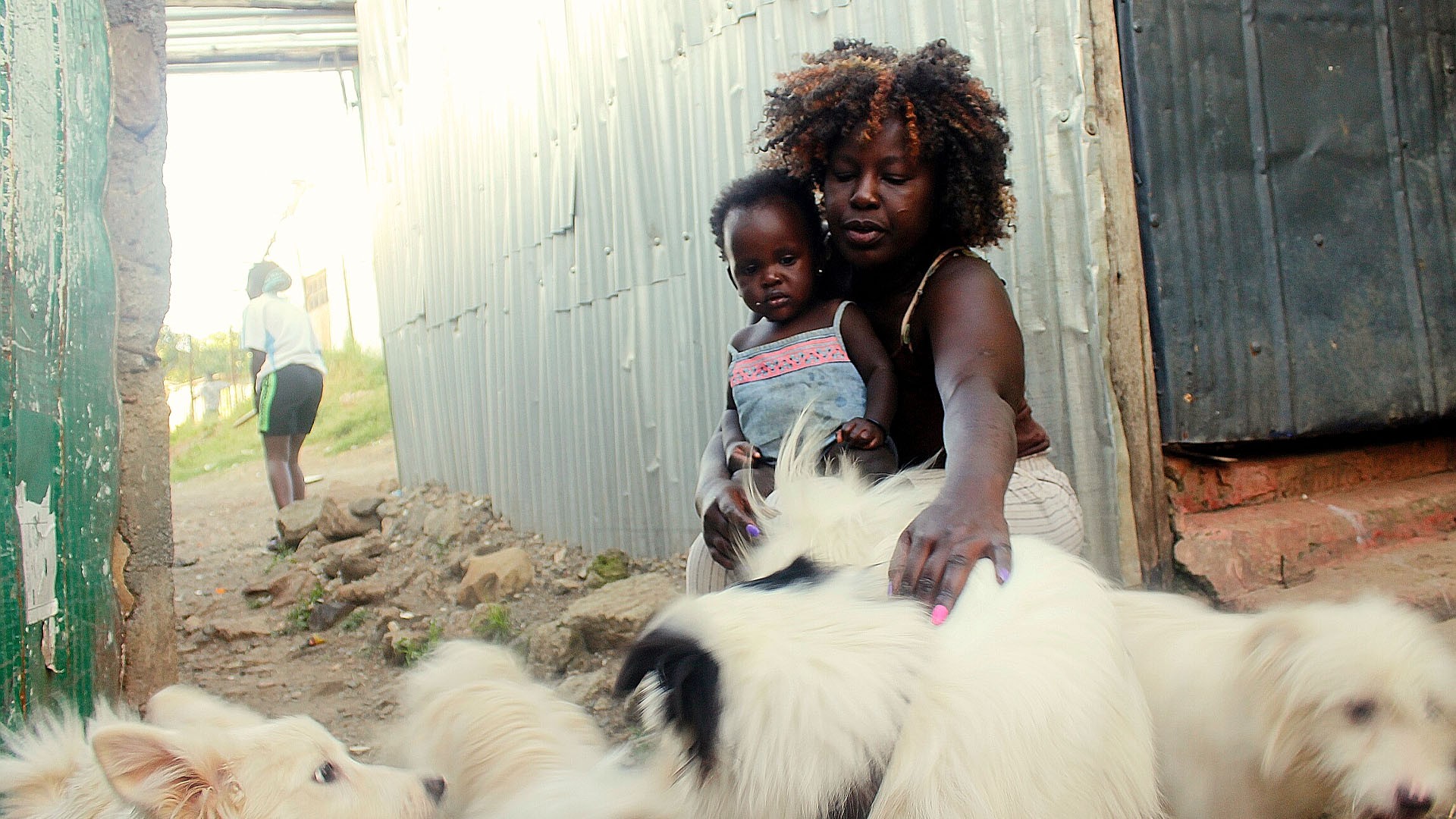 Advella Waringa Wanjiru and her grandchild watching after her dogs.